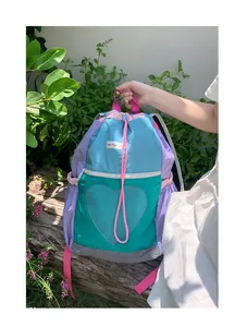 Dettaglio dello zaino multicolore con coulisse, rete a cuore ed etichetta del brand