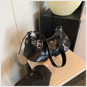 Macro detail of black glossy PU leather underarm bag with biker buckles and silver eyelets