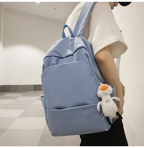 Detail view of water-resistant blue backpack with a cute white duck plush charm attached