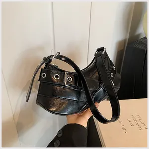 Detail of black glossy crescent shoulder bag with silver eyelets and buckle accents
