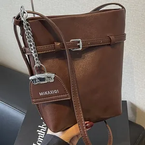 Dark brown leather bucket bag with silver buckle and metal chain strap for women
