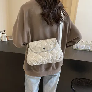 Minimalist cream quilted crossbody bag with adjustable strap worn by model in a studio