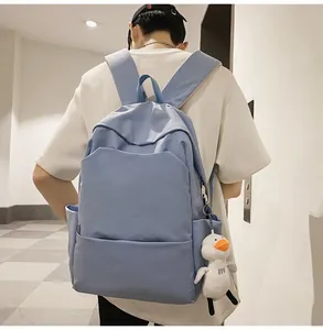 Man wearing a large Morandi blue waterproof backpack with a cute white duck pendant