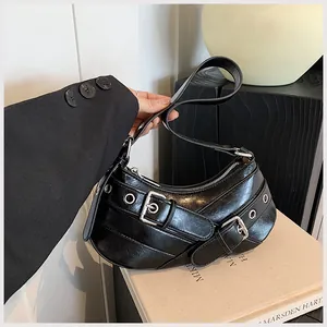 Detail of black crescent shoulder bag with silver grommets and punk style buckle