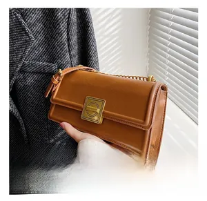Detailed macro view of brown vintage leather bag with a gold square lock and chain strap
