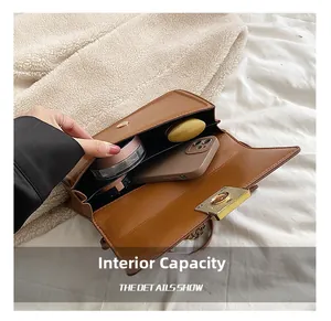 Internal capacity of brown leather crossbody bag with metal lock showing phone and makeup