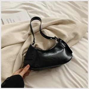 Detail of minimalist black hobo bag in glossy finish with adjustable silver buckle strap