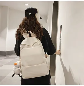 Side view of an off-white waterproof backpack with a cute duck keychain accessory