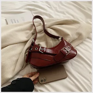 Detail view of burgundy underarm bag with metal eyelets and side buckle accents
