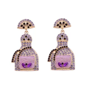 Close-up of gold alloy tequila bottle earrings with purple rhinestones and engraving