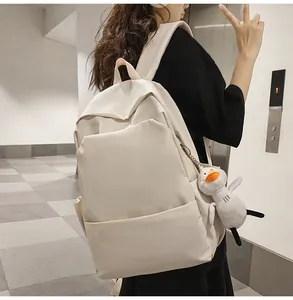 Detail view of a beige waterproof backpack with a cute white duck plush pendant