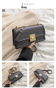 Detail of gray leather small square bag with gold metal clasp and chain strap