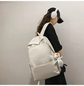 Close-up of beige minimalist waterproof backpack featuring a cute white duck plush charm