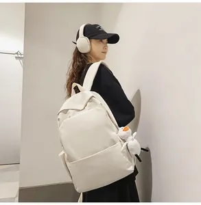 Detail view of large cream waterproof backpack with a cute white duck plush charm