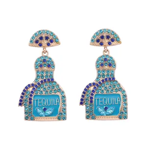 Detailed view of gold-tone tequila bottle earrings with blue rhinestones and lettering