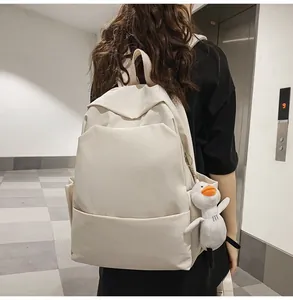 Detail view of cream waterproof backpack with a cute duck plush pendant in a daily setting