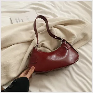 Detail of dark red underarm bag in glossy faux leather with vintage cracked texture