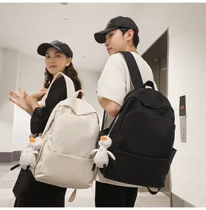 Detail of minimalist waterproof backpacks in cream and black with cute duck pendant