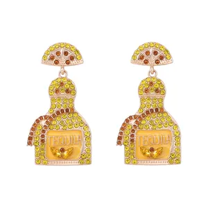 Detailed view of gold earrings with tequila bottle charms and crystal lemon slices