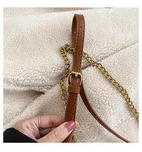 Detail of brown PU leather shoulder strap with gold chain and metal buckle