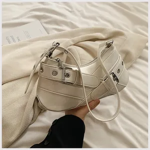 Close-up of cream underarm bag with decorative metal buckles and silver eyelets detail