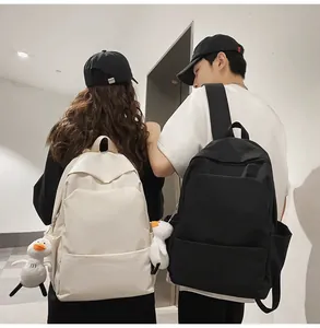 Rear view of couple wearing minimalist waterproof backpacks with cute duck pendants