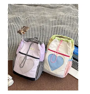 Dettaglio di zaini da trekking colorati con tasche a rete a cuore e chiusura a coulisse