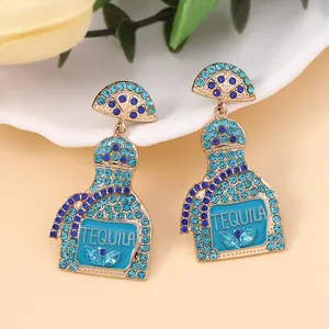 Detail of tequila bottle earrings with blue crystals and lemon slice charms