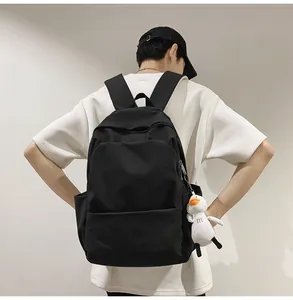 Rear view of man wearing minimalist black waterproof backpack with plush duck charm