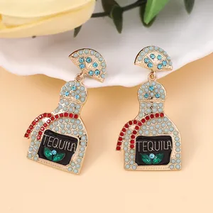 Close-up of tequila bottle earrings with crystal rhinestones and blue pearls