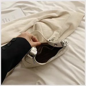Detail view of the white crescent bag interior with striped lining and metallic zipper