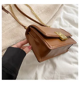 Detail of dark brown faux leather bag featuring a gold turn-lock and accordion structure
