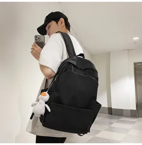 Detail view of a black waterproof backpack with a white plush duck charm on the zipper