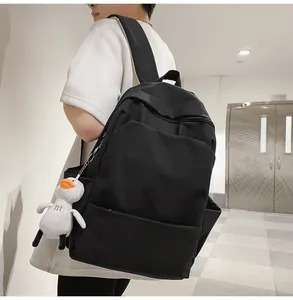 Side view of black waterproof backpack with cute white duck plush toy keychain