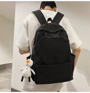 Waterproof black nylon backpack with a cute white duck plush charm shown on model back