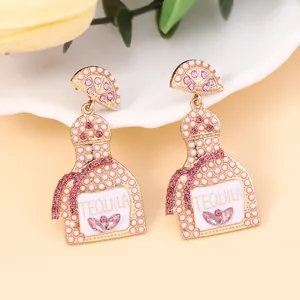Macro detail of Tequila bottle earrings with pink rhinestones and lemon slice accent