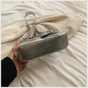 Close-up of metallic silver underarm bag showing the wide bottom and buckle detail