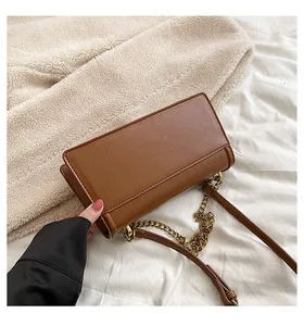 Close-up of brown PU leather texture and gold chain strap on a minimalist shoulder bag