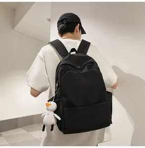 Detail of minimalist black waterproof backpack featuring a cute white duck plush keychain