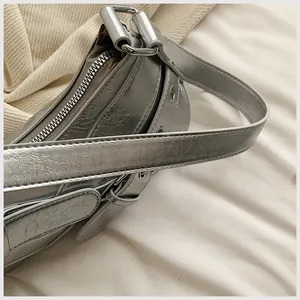 Macro view of metallic silver handbag featuring fine wrinkled texture and adjustable strap