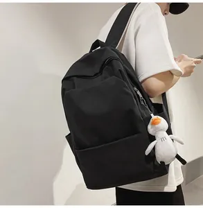 Detail view of black waterproof backpack featuring a cute white plush duck charm on the side