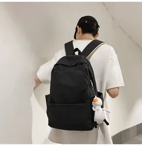 Close-up of black waterproof backpack with cute white duck plush charm pendant accessory