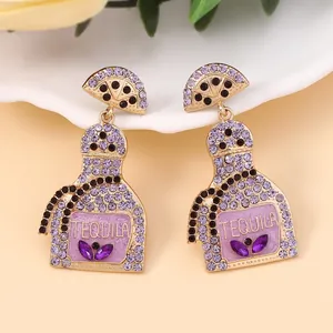Detailed macro view of purple rhinestone tequila bottle earrings with lemon slice design
