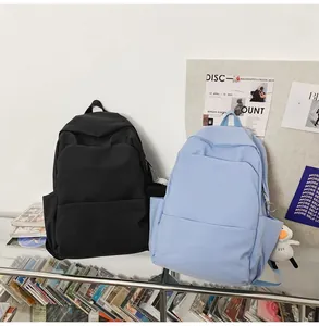 Detail view of large waterproof backpacks in black and light blue with plush duck pendant