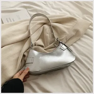 Detail of metallic silver underarm bag showing the leather texture and side stitching