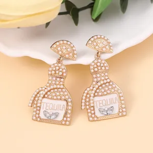 Detail of tequila bottle earrings with faux pearls and sparkling crystal leaf accents