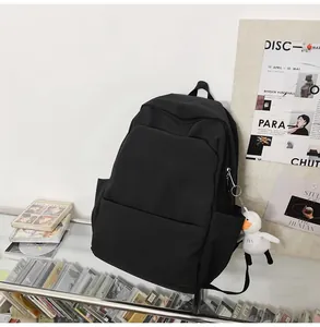 Detail view of black waterproof backpack featuring a cute white plush duck charm on a shelf