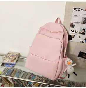 Pink waterproof backpack with a white duck plush charm shown in a cozy indoor lifestyle setting