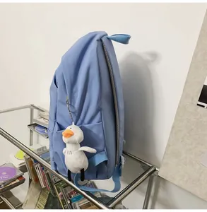 Light blue waterproof nylon backpack detail with a cute white duck plush keychain