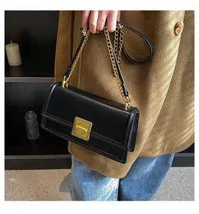 Detail of vintage black leather box bag featuring a luxury gold clasp and chain strap
